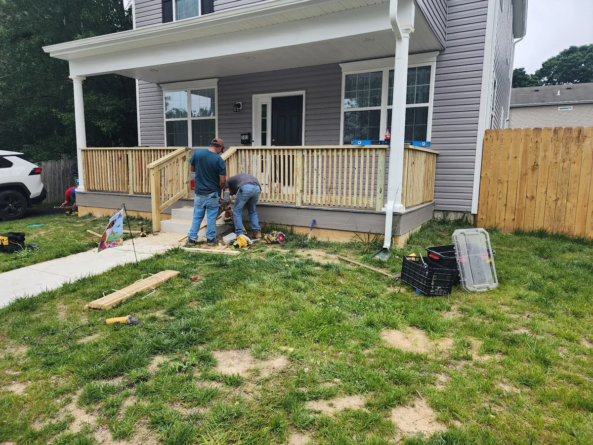 Fence installation crew building wood railing on residential porch