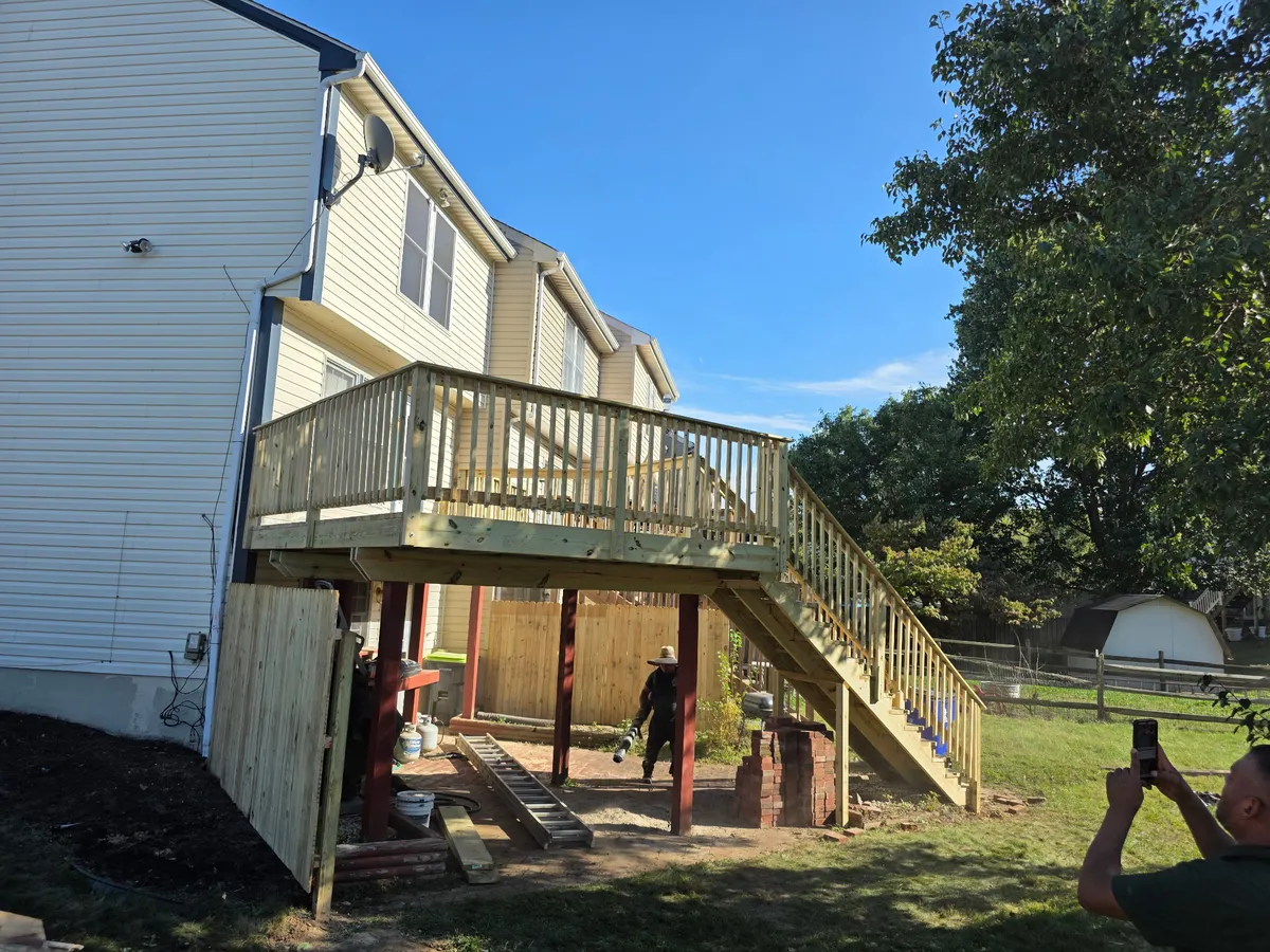 Elevated pressure-treated wood deck with stairs and railing built by TWO MEN